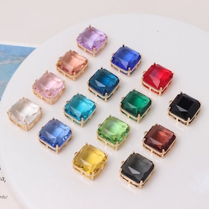 Può includere: Assortimento di 15 ciondoli quadrati in vetro con cornici in metallo dorato. I ciondoli sono di vari colori, tra cui rosa, blu, verde, rosso, giallo e trasparente.