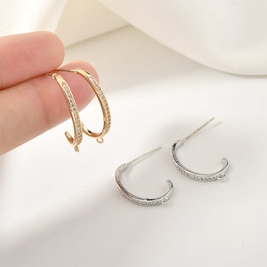 May include: Two pairs of hoop earrings with a clear crystal design. One pair is gold and the other is silver.