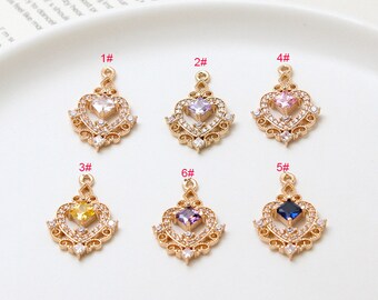May include: Six gold-colored heart-shaped pendants with different colored center stones: clear, purple, pink, yellow, dark blue, and light purple. Each pendant is adorned with small, clear crystals and a loop at the top for hanging.