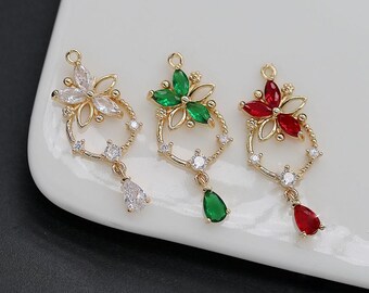 May include: Three gold-toned floral charms with colorful gemstone accents. Each charm features a flower design with clear, green, and red petals, surrounded by a beaded circle and a teardrop-shaped gemstone pendant. Ideal for jewelry making.