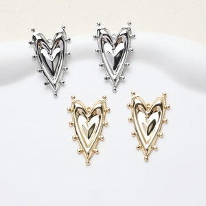May include: Four heart-shaped charms with a textured surface. Two charms are silver and two are gold.