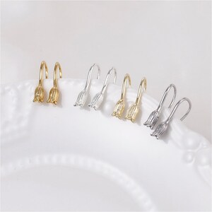 May include: Three pairs of silver and gold flower-shaped earrings with a hook fastening.
