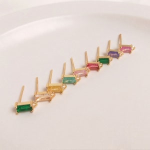 May include: Assortment of gold earring findings with colorful rectangular stones. The stones are in shades of green, pink, purple, and yellow.