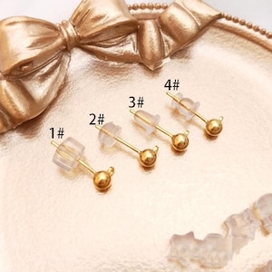 Peut inclure: Quatre paires de clous d'oreilles en or avec des dos en plastique transparent. Les clous d'oreilles sont numérotés de 1 à 4.