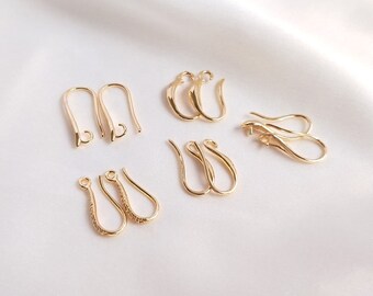 May include: A set of six gold-toned earring hooks. The hooks are in various styles, including simple loops, teardrop shapes, and hooks with a textured finish.