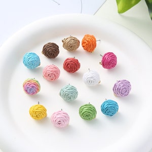 May include: Assortment of 14 colourful paper rope earrings in various colours, including pink, blue, green, yellow, orange, red, white, and brown. The earrings are displayed on a white surface.