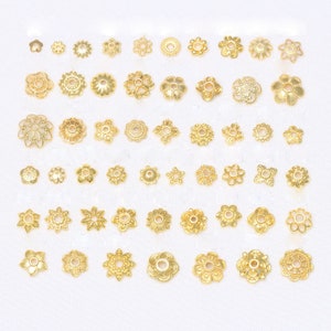 Könnte beinhalten: Eine Sammlung kleiner, goldfarbener Metallblütenperlen. Die Perlen variieren in Größe und Design, mit aufwendigen Details und einem glänzenden Finish. Das Sortiment umfasst verschiedene Blumenmuster, perfekt für die Schmuckherstellung oder Bastelprojekte.