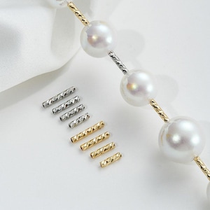 May include: A strand of white pearls with a silver and gold chain. The chain has a textured design. There are also several silver and gold connector pieces.