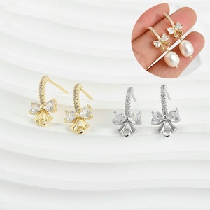 Peut inclure: Deux paires de boucles d'oreilles en forme de nœud or et argent avec des accents de cristal transparent. Les boucles d'oreilles ont une boucle en bas pour attacher un charme ou un pendentif.