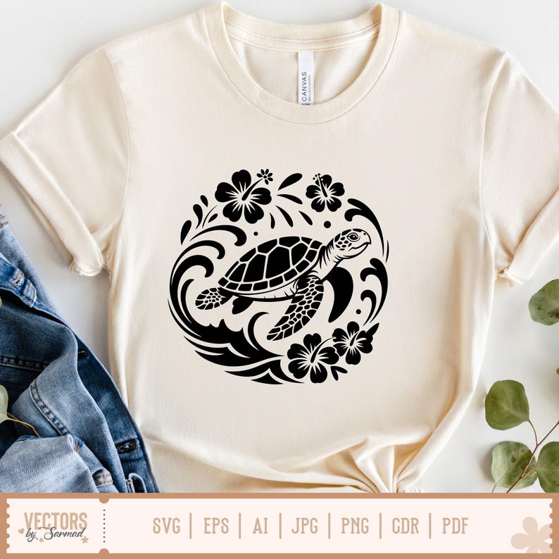 May include: Cream-colored t-shirt featuring a black turtle design within a circular floral and wave pattern. The turtle has a detailed shell and is surrounded by hibiscus flowers. The shirt is made of a soft material.
