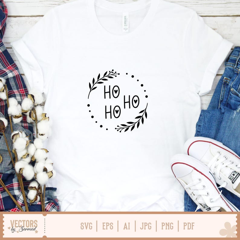 Puede incluir: Una camiseta blanca de manga corta con un estampado gr&aacute;fico negro en el pecho. El dise&ntilde;o consiste en el texto HO HO HO con corazones en el centro de las letras O, encerrado en un marco circular de hojas y peque&ntilde;os puntos.