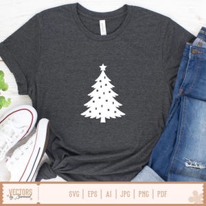 Puede incluir: Una camiseta de manga corta en color gris jaspeado oscuro con un gr&aacute;fico blanco de un &aacute;rbol de Navidad con una estrella en la punta y peque&ntilde;os adornos cuadrados. La prenda se muestra junto a unos vaqueros azules y zapatillas de lona blancas.