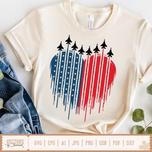 Könnte beinhalten: Ein weißes T-Shirt mit einem rot-weiß-blauen Herzdesign. Das Herz besteht aus Streifen und Sternen, über denen eine Silhouette von Kampfjets fliegt. Der Text "VECTORS by Sarmad" befindet sich am unteren Rand des Bildes.