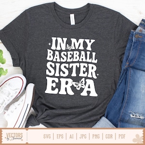 Puede incluir: Una camiseta gris oscuro con texto blanco que dice "In My Baseball Sister Era" con un gr&aacute;fico de mariposa.