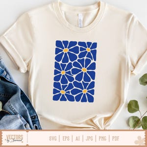 Op de afbeelding: Cr&egrave;mekleurig T-shirt met een rechthoekig ontwerp van blauwe bloemen met gele centra. Het shirt heeft korte mouwen en een ronde hals. De onderkant van het shirt toont de tekst "VECTORS by Sarmad" en bestandstype-opties: SVG, EPS, AI, JPG, PNG en PDF.