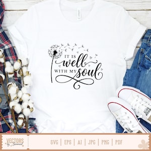 Puede incluir: Camiseta blanca con un dise&ntilde;o de diente de le&oacute;n negro y la frase "IT IS well WITH MY soul" en una elegante escritura. El dise&ntilde;o incluye peque&ntilde;os acentos de coraz&oacute;n. La camiseta se muestra con vaqueros azules y zapatillas blancas.