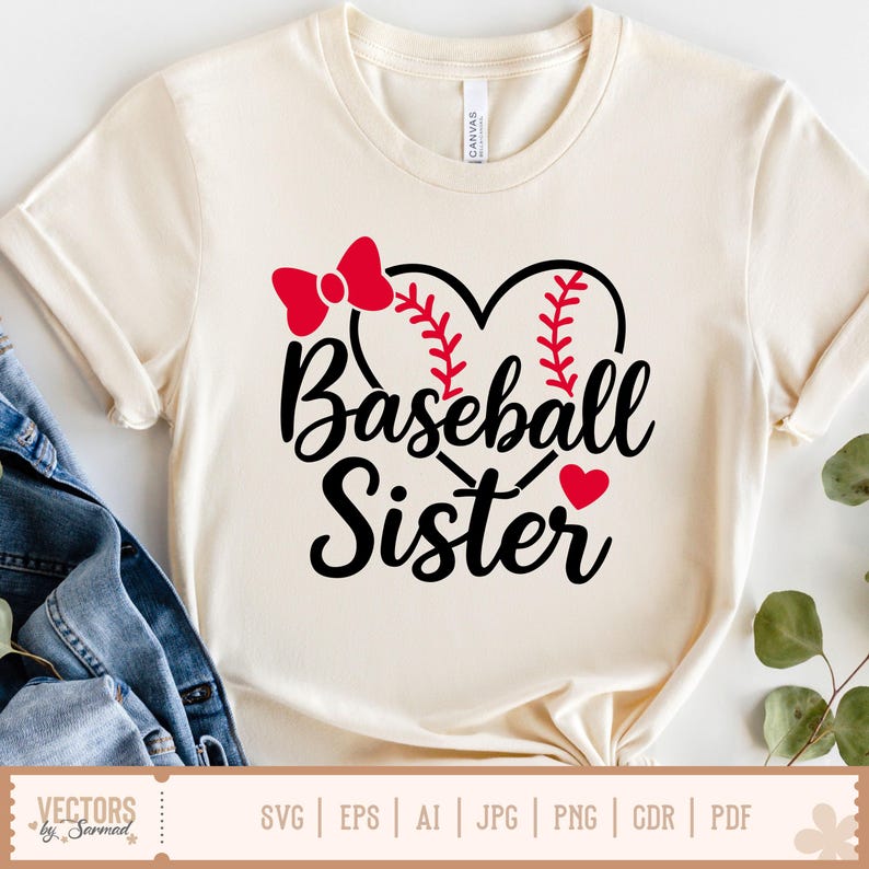 Puede incluir: Una camiseta blanca con un lazo rojo y una pelota de b&eacute;isbol en forma de coraz&oacute;n. El texto "Baseball Sister" est&aacute; escrito en letra cursiva negra.