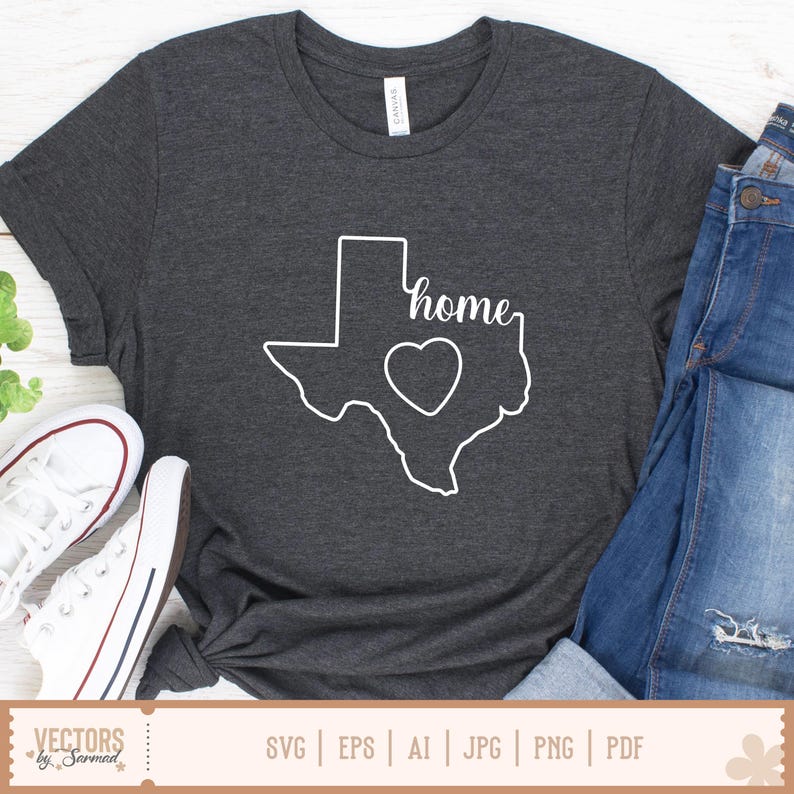 May include: Dark gray t-shirt featuring a white outline of the state of Texas with a heart and the word "home". The shirt is paired with blue jeans and white sneakers. The shirt is made of a soft material.