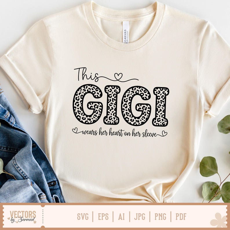 Pu&ograve; includere: T-shirt color crema con la scritta "This GIGI" in corsivo nero e stampa leopardata. La frase "wears her heart on her sleeve" &egrave; sotto. La maglietta ha le maniche arrotolate ed &egrave; abbinata a una giacca di jeans.