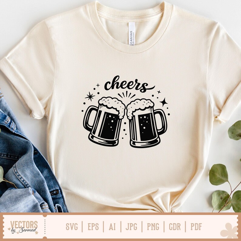 May include: Cream-colored t-shirt featuring a black graphic of two beer mugs with foamy tops, and the word "cheers" above them. The design includes stars and decorative elements. The shirt is made of a soft material.