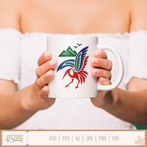 May include: White ceramic mug featuring a colorful bird design with green mountains and blue birds. The bird has red, blue, and green details. The mug is held by a person.