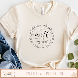 Puede incluir: Camiseta color crema con el texto "IT IS well with my soul" en un dise&ntilde;o floral negro circular. La camiseta est&aacute; hecha de un material suave y es adecuada para uso casual. La parte inferior de la camiseta est&aacute; anudada.