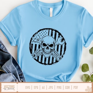May include: Light blue t-shirt featuring a black and white graphic of a skull holding two wrenches, set against a circular American flag design. The shirt is a crew neck and has short sleeves. The bottom of the shirt has the text "SVG | EPS | AI | JPG | PNG | CDR | PDF".
