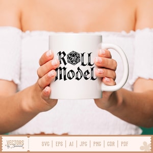 May include: A white ceramic mug featuring the text "Roll Model" in a gothic font, with a black and white D20 die graphic. The mug is held by a person wearing a white off-the-shoulder top. The mug is a standard size.