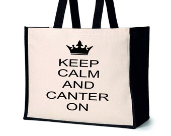 May include: A white canvas tote bag with black handles and a black trim. The bag has a black crown and the text "Keep Calm and Canter On" printed on the front.