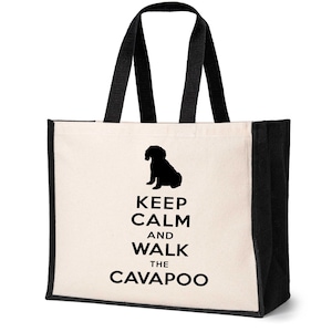 May include: A white canvas tote bag with black handles and black trim. The bag features a black silhouette of a dog and the text "Keep Calm and Walk the Cavapoo".