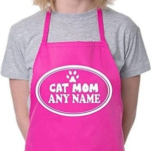 May include: Pink cat mom apron with a white oval that says "Cat Mom" and a paw print above the text. The oval also has space for a name. The apron has a large pocket.