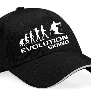 May include: Black baseball cap with a white graphic of the evolution of man culminating in a skier. The text "EVOLUTION SKIING" is printed below the graphic.