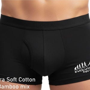 May include: Black boxer briefs featuring an elastic waistband with the embossed text ALPHA. The right leg displays a white graphic showing the evolution of a rugby player with the text EVOLUTION Rugby League. Text at the bottom reads Ultra Soft Cotton Bamboo mix.