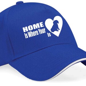 May include: A royal blue baseball cap with a white brim and a white graphic that says "HOME is Where Your ___ is" with a heart containing a silhouette of a dog.