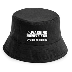 Könnte beinhalten: Schwarzer Bucket Hat mit einem weißen Warnschild, auf dem steht "WARNING GRUMPY OLD GIT APPROACH WITH CAUTION!"