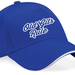 Puede incluir: Una gorra de béisbol azul real con visera blanca y texto bordado en blanco que dice "Old Gits Rule".