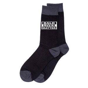 May include: Black and grey socks with a white rectangle on the top of the sock that says "Bald Lives Matter".