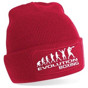 May include: Red knit beanie with a white patch featuring a stick figure evolution of a boxer with the text "EVOLUTION BOXING".