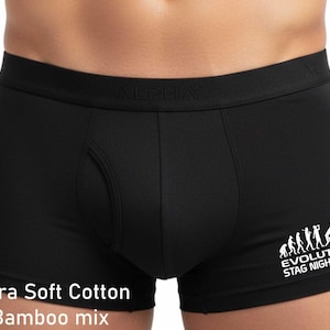 May include: Black boxer briefs featuring a white graphic print of the evolution of a human figure ending at a toilet with the text "EVOLUTION STAG NIGHT" and the text "Ultra Soft Cotton Bamboo mix" printed in white on the lower left side.