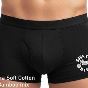 May include: Black boxer briefs featuring a wide elastic waistband with the word ALPHA embossed. The fabric is a cotton and bamboo mix. A white graphic on the lower right leg depicts a motorcycle with the text BORN TO RIDE arched around it.
