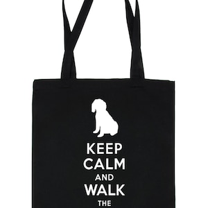 Könnte beinhalten: Schwarze Einkaufstasche mit weißem Text, der "Keep Calm and Walk the Cavapoo" lautet. Oberhalb des Textes befindet sich eine weiße Silhouette eines Cavapoo-Hundes.