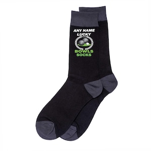 May include: A pair of black socks with gray accents on the toe, heel, and cuff. The socks feature the text "ANY NAME LUCKY" above a graphic of bowling balls and a laurel wreath, with "BOWLS SOCKS" below in green.