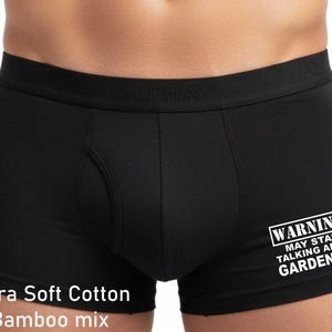 May include: Black boxer briefs featuring a wide elastic waistband with the embossed text ALPHA. The front leg displays white text that reads WARNING! MAY START TALKING ABOUT GARDENING. The fabric is labelled as an Ultra Soft Cotton Bamboo mix.