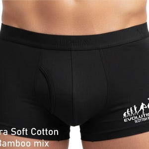 May include: Black boxer briefs featuring an elastic waistband with the embossed text ALPHA. The right leg displays a white graphic showing the evolution of a rugby player and the text EVOLUTION SCOTTISH RUGBY. Text at the bottom reads Ultra Soft Cotton Bamboo mix.