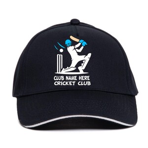 May include: A navy blue baseball cap with a white trim, featuring a cricket design. The design includes a batter, ball, and stumps, with the text "CLUB NAME HERE CRICKET CLUB" in white.
