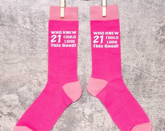 Könnte beinhalten: Ein Paar rosa Socken mit weißem Text, der lautet: "Wer hätte gedacht, dass 21 so gut aussehen kann!"