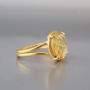 K&ouml;nnte beinhalten: Ein goldener Ring mit einem gro&szlig;en, ovalen, gelben Edelstein, der in einer Krappenfassung sitzt. Der Ringarm ist d&uuml;nn und hat eine geteilte Schiene.