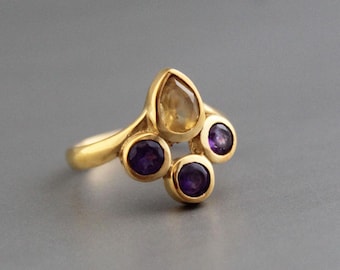 May include: A gold ring with a teardrop-shaped topaz gemstone and four round amethyst gemstones.