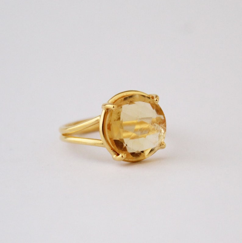 K&ouml;nnte beinhalten: Ein goldener Ring mit einem gro&szlig;en, ovalen, hellgelben Edelstein.
