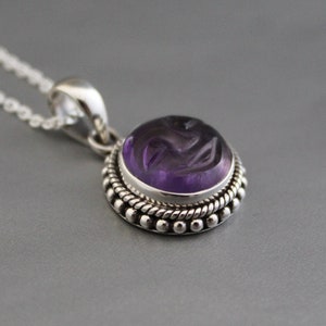 Può includere: Una collana d'argento con un ciondolo in ametista viola. Il ciondolo è incastonato in una ghiera d'argento e presenta un design dettagliato.